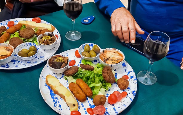 Street food dishes with olives, cheese, and wine on a guided tour in Syracuse.