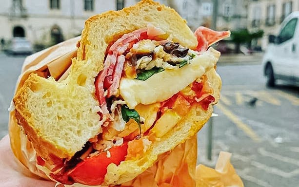 Sandwich with meats and vegetables on a street food tour in Syracuse.