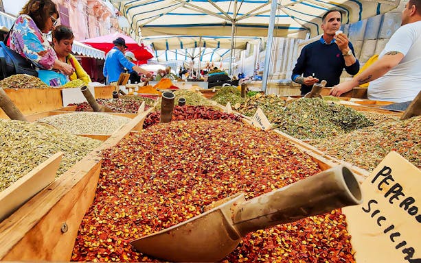 Spice market stall with various colorful spices on display during a street food tour in Syracuse.