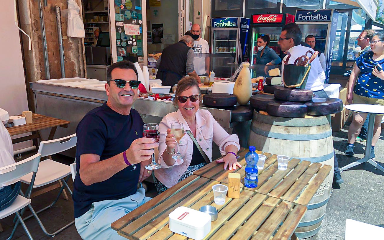 Couple enjoying wine at a street food stall in Syracuse during a guided tour.