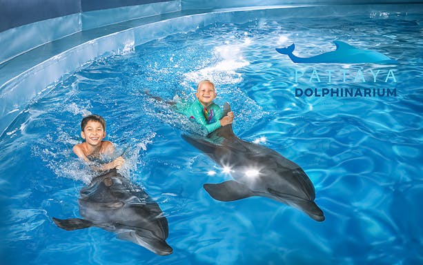 Children swimming with dolphins at Pattaya Dolphinarium, Thailand.