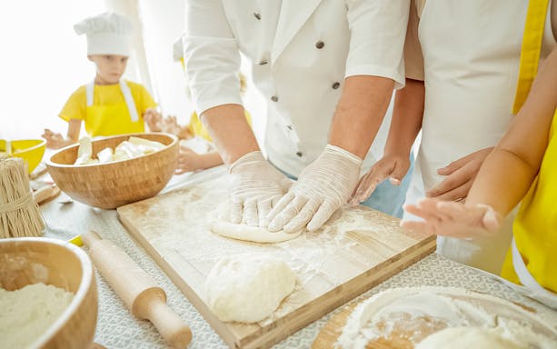 Hands kneading dough during a pizza making class in Naples.