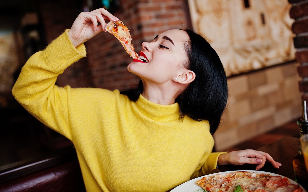 Person enjoying a slice of pizza during a food and wine tasting in Naples.