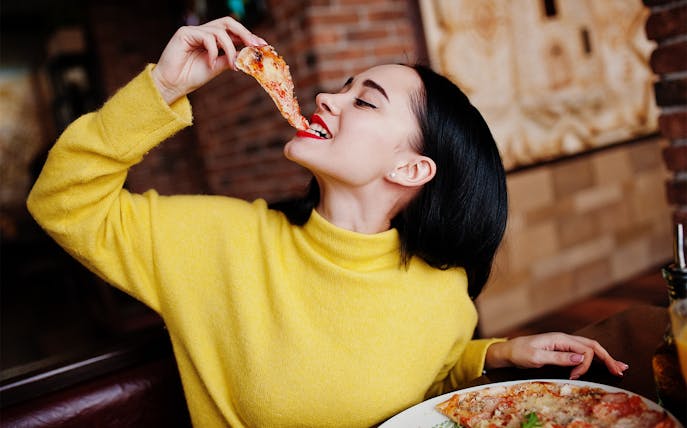 Person enjoying a slice of pizza during a food and wine tasting in Naples.