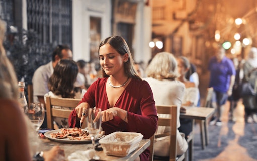 Dining experience in Naples with a woman enjoying a meal at an outdoor restaurant.