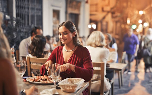 Dining experience in Naples with a woman enjoying a meal at an outdoor restaurant.