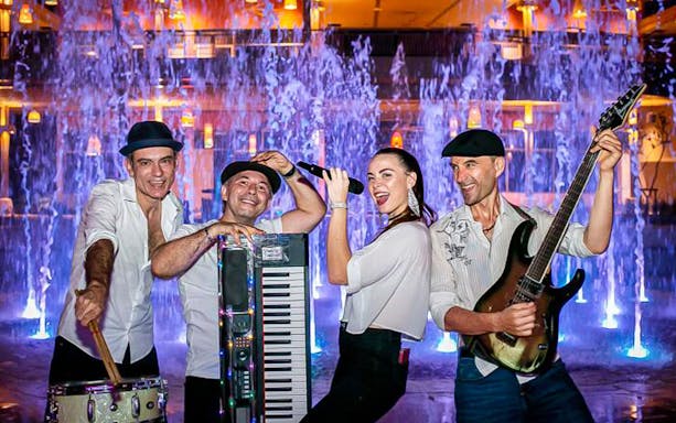 Musicians performing at Blue Tree Water Park with colorful fountains in the background.