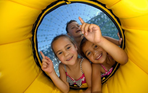 Children enjoying Zorb Rotorua VIP Experience inside a yellow inflatable ball.