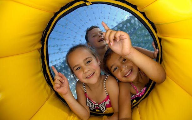 Children enjoying Zorb Rotorua VIP Experience inside a yellow inflatable ball.