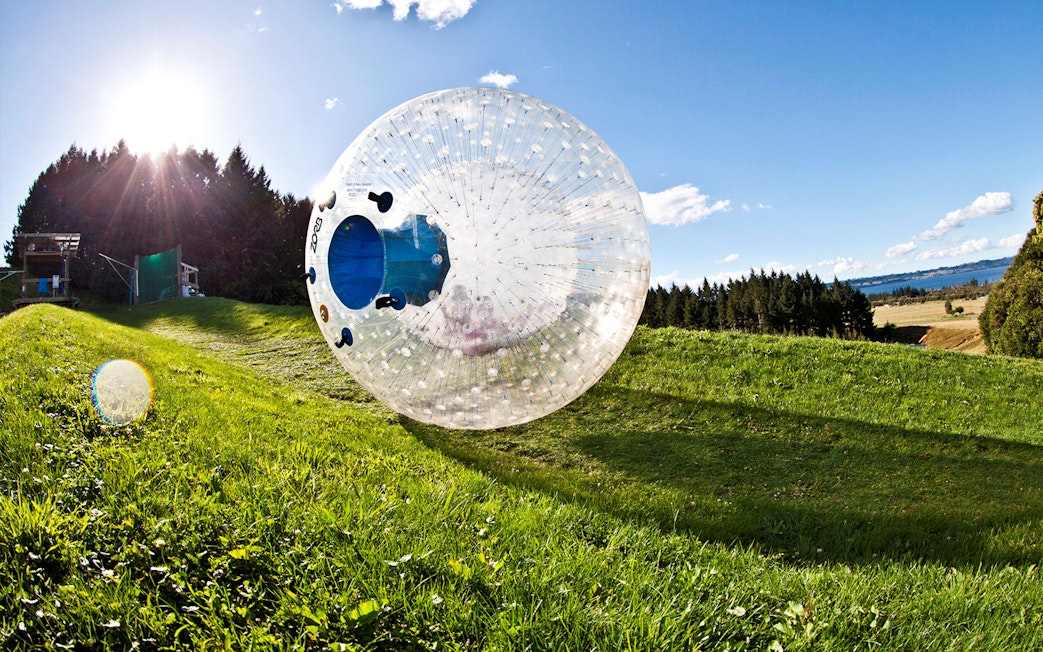 ZORB ball rolling down a grassy hill at ZORB Rotorua, New Zealand.