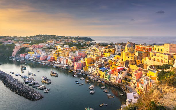 Colorful buildings and boats in Marina Corricella, Procida Island, Italy, viewed from above.