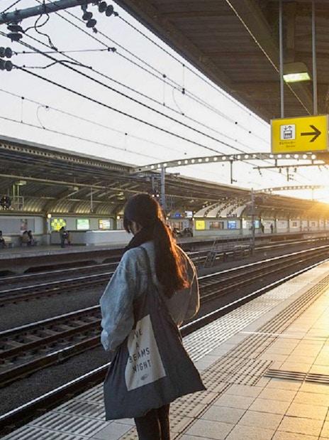 Person waiting at Tokyo train station platform during sunset.