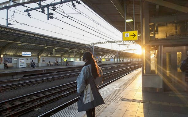 Person waiting at Tokyo train station platform during sunset.