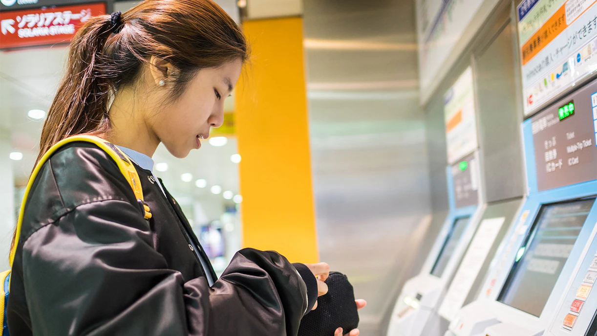 Person using ticket machine at Fukuoka City subway station.