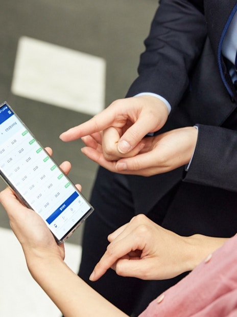 People checking train schedules on a phone at Incheon International Airport.