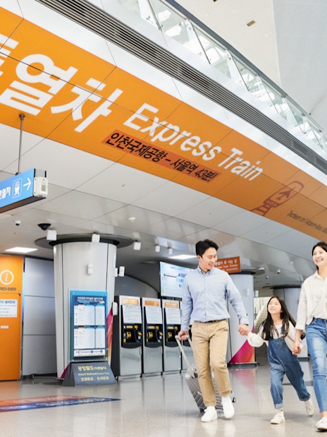 Family walking towards Express Train at Incheon International Airport for round-trip travel.