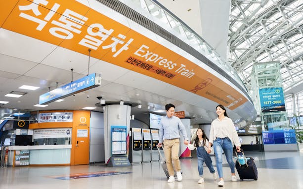 Family walking towards Express Train at Incheon International Airport for round-trip travel.