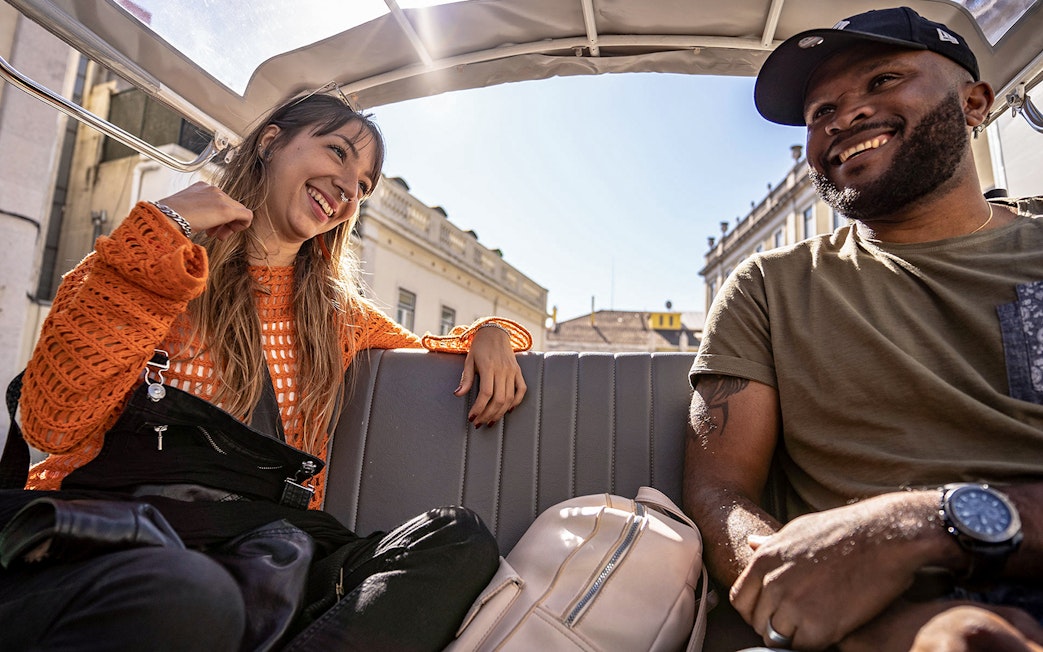 Two people enjoying a private tuk-tuk tour in Lisbon along the 28 tram route.