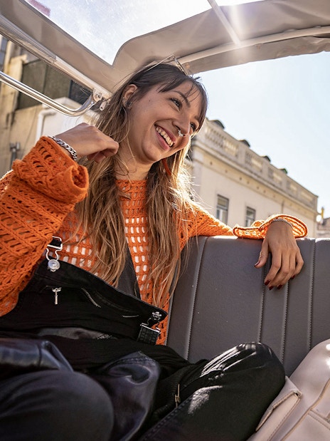Two people enjoying a private tuk-tuk tour in Lisbon along the 28 tram route.