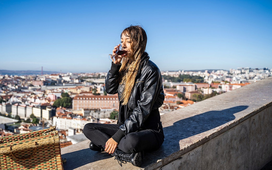 Person enjoying a drink with a view of Lisbon on a private Tuk-Tuk tour following the 28 tram route.