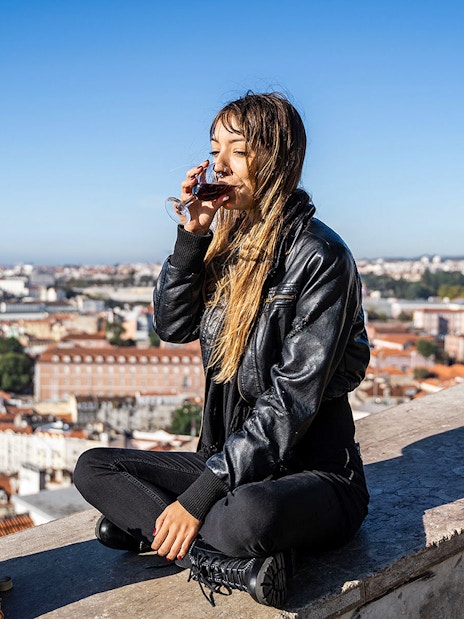 Person enjoying a drink with a view of Lisbon on a private Tuk-Tuk tour following the 28 tram route.