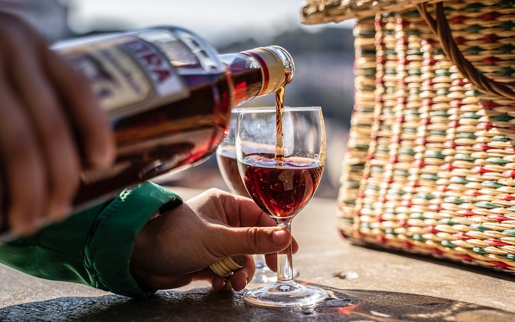 Pouring wine into a glass during a private Tuk-Tuk tour in Lisbon.