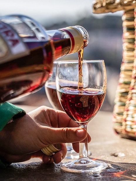 Pouring wine into a glass during a private Tuk-Tuk tour in Lisbon.