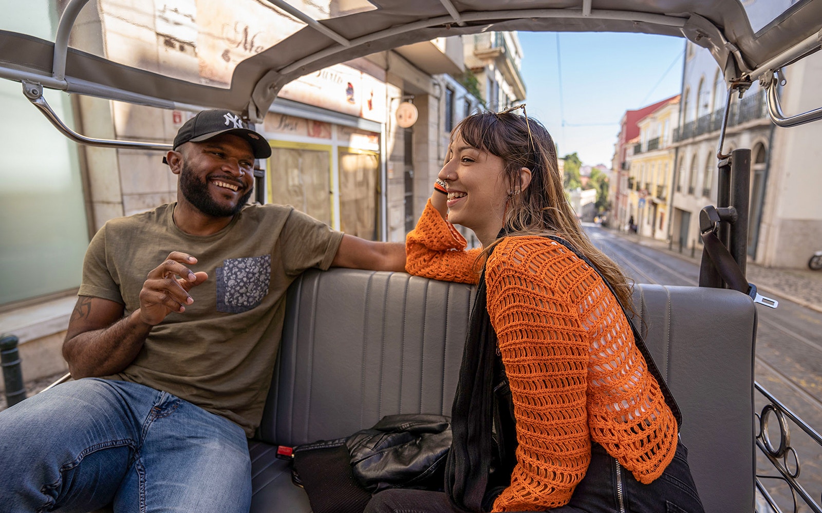 Two people enjoying a tuk-tuk ride along Lisbon's 28 tram route.