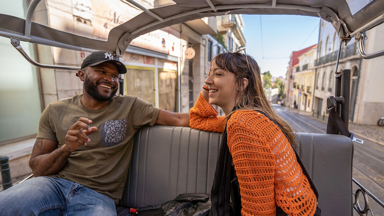 Two people enjoying a tuk-tuk ride along Lisbon's 28 tram route.