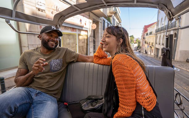 Two people enjoying a tuk-tuk ride along Lisbon's 28 tram route.