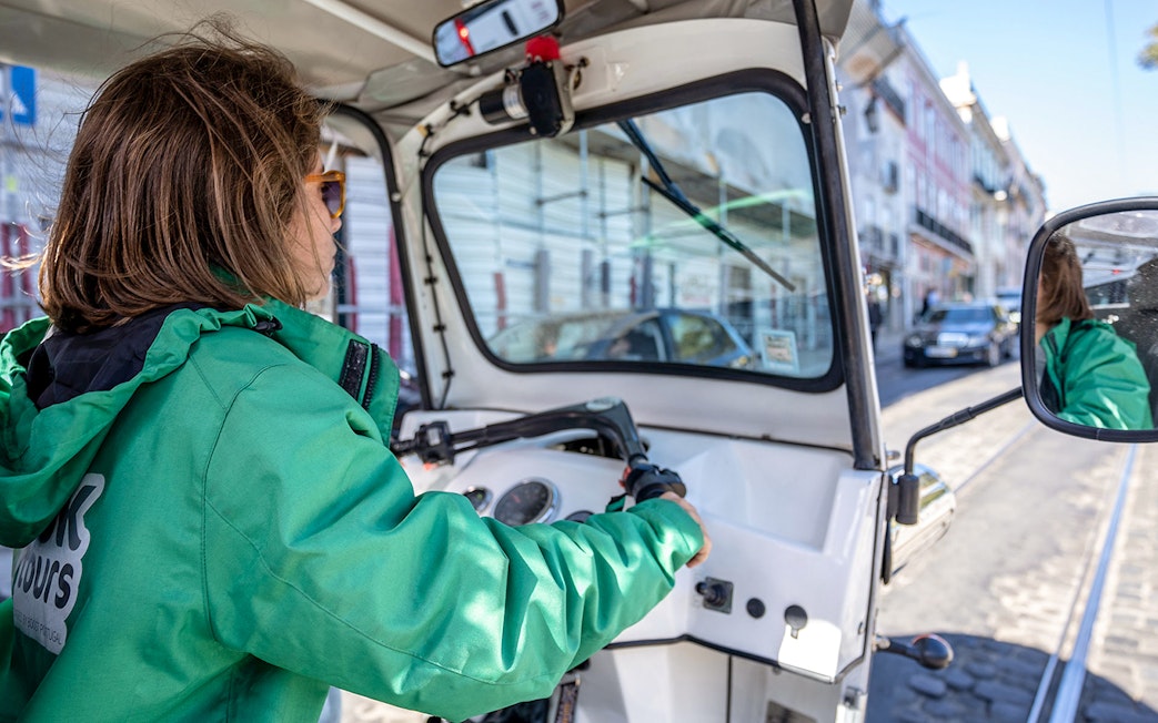 Tuk-tuk driver navigating Lisbon streets along the 28 tram route.