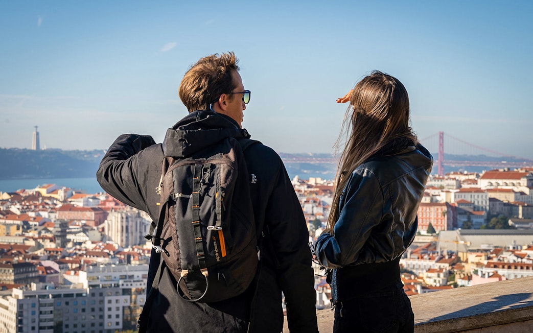 Tourists overlooking Lisbon with the 25 de Abril Bridge in the background.