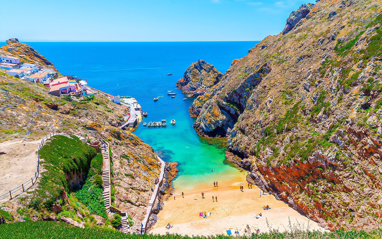 Berlenga Grande Island beach with boats and cliffs, part of Lisbon cave tour.