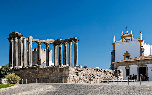 Roman Temple of Évora and nearby church on a sunny day.