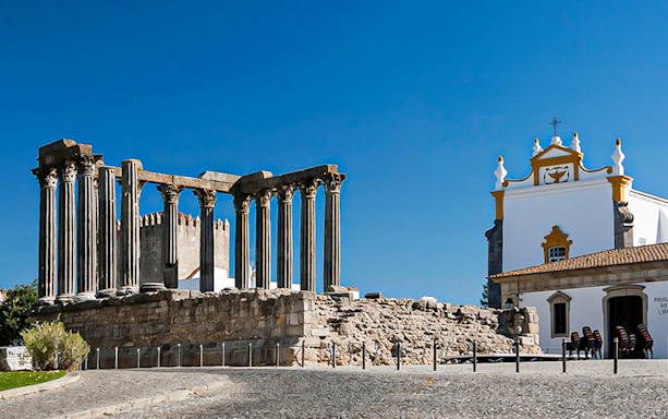 Roman Temple of Évora and nearby church on a sunny day.