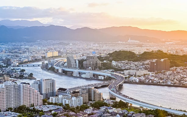 Fukuoka cityscape with river and highway at sunset, view relevant to Sugoca IC Card travel.