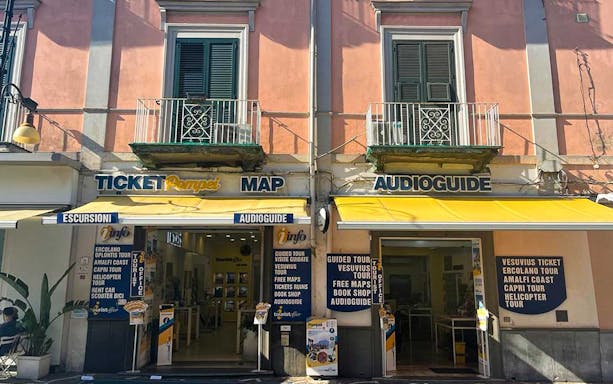 Ticket office in Pompeii offering tours to Amalfi and Positano, with maps and audioguides available.