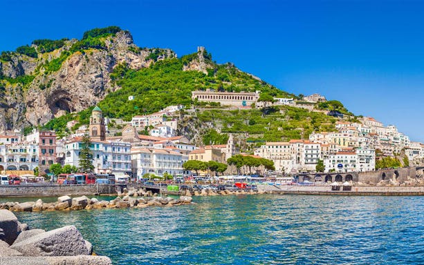 Amalfi coast view with colorful buildings and lush hills from the sea, Italy.