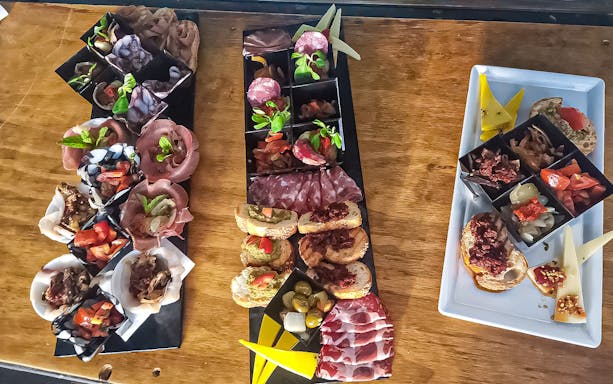 Aperitif platters with assorted meats, cheeses, and bruschetta on Ortigia Island sunset boat tour.