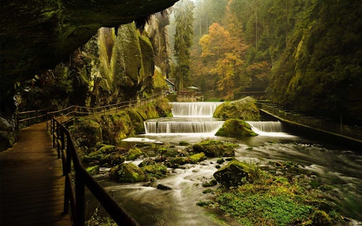 Wooden path along a river with waterfalls in Bohemian Switzerland National Park.
