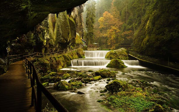 Wooden path along a river with waterfalls in Bohemian Switzerland National Park.