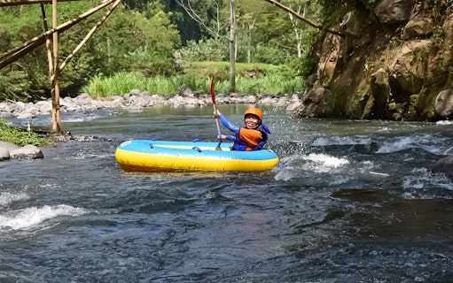 White water rafting on Telaga Waja River with a person paddling in a yellow raft.