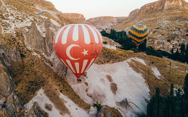 Hot air balloons over Cappadocia's unique rock formations during a 2-day tour from Istanbul.