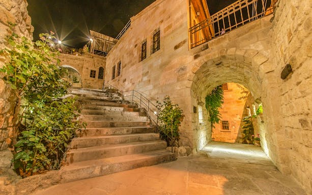 Stone steps and archway at Dere Suites Cappadocia, Turkey, illuminated at night.