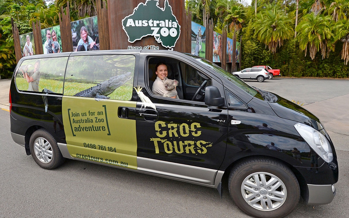Tourists boarding a bus for their transfer from Brisbane to Australia Zoo, holding entry tickets in hand