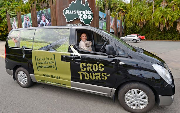 Tourists boarding a bus for their transfer from Brisbane to Australia Zoo, holding entry tickets in hand