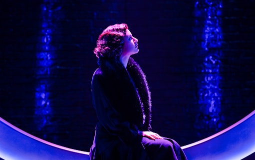 Performer in dramatic lighting on stage for "Funny Girl" show.