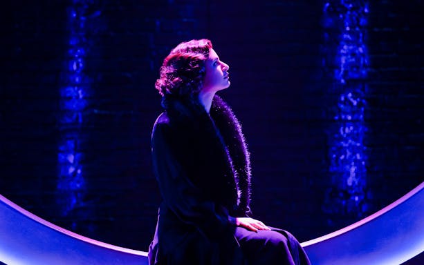 Performer in dramatic lighting on stage for "Funny Girl" show.