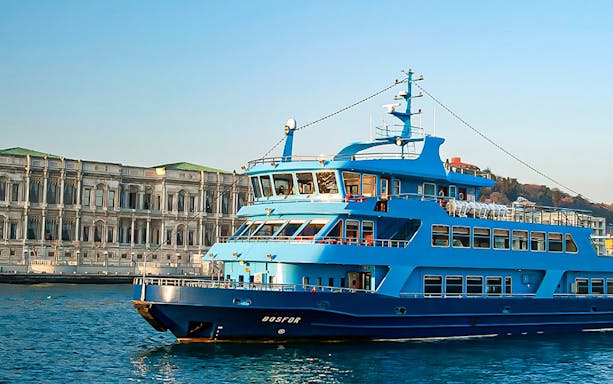 Blue cruise ship on the Bosphorus near historic Istanbul building, Turkey.