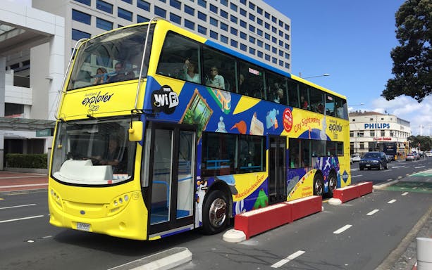 Auckland Explorer Bus on city street near Sky Tower.